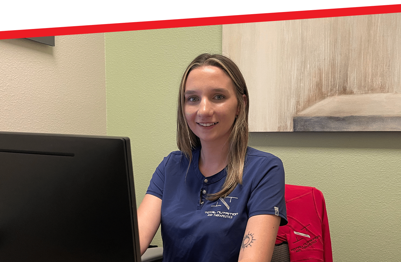 a woman sitting in front of a laptop and smiling at the camera
